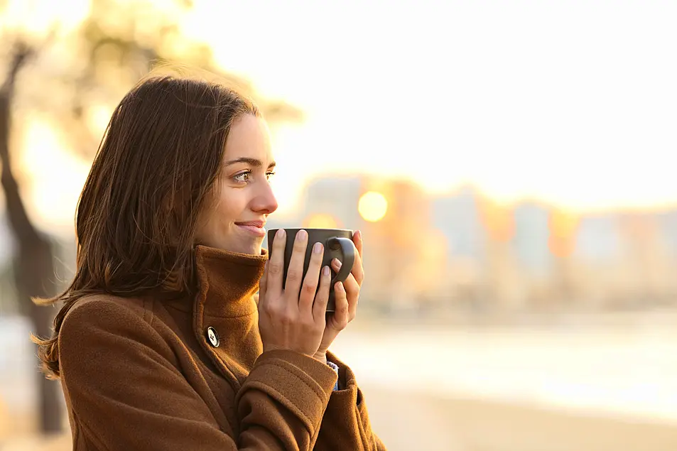 Woman outside in the morning holding a cup of coffee