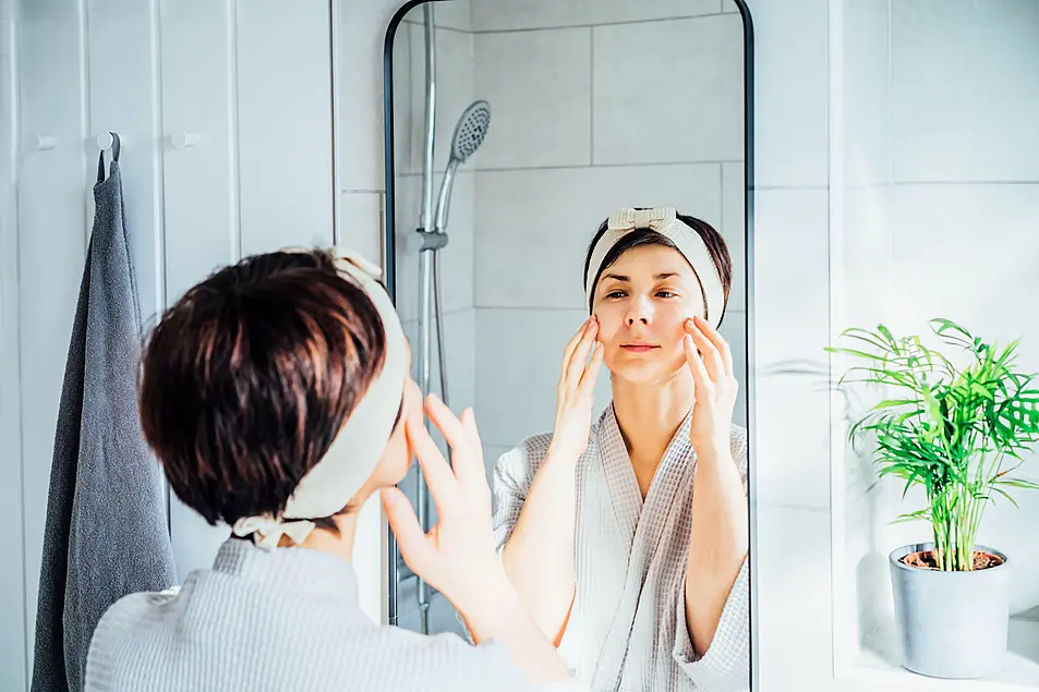 woman doing face massage/yoga in the bathroom mirror