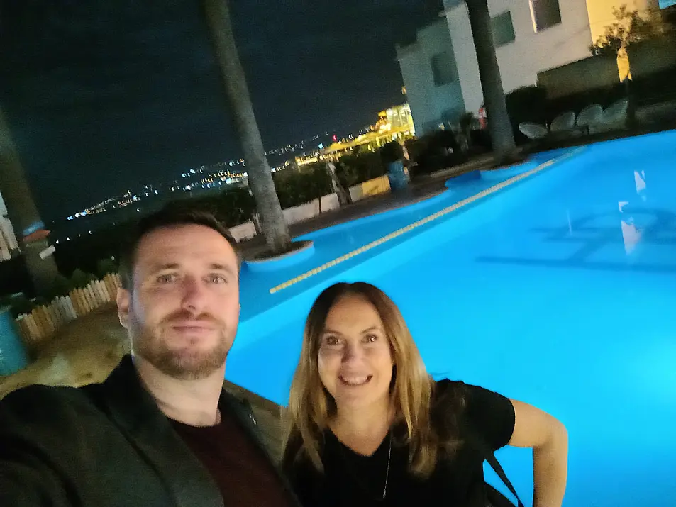 A man and woman smiling in front of a swimming pool