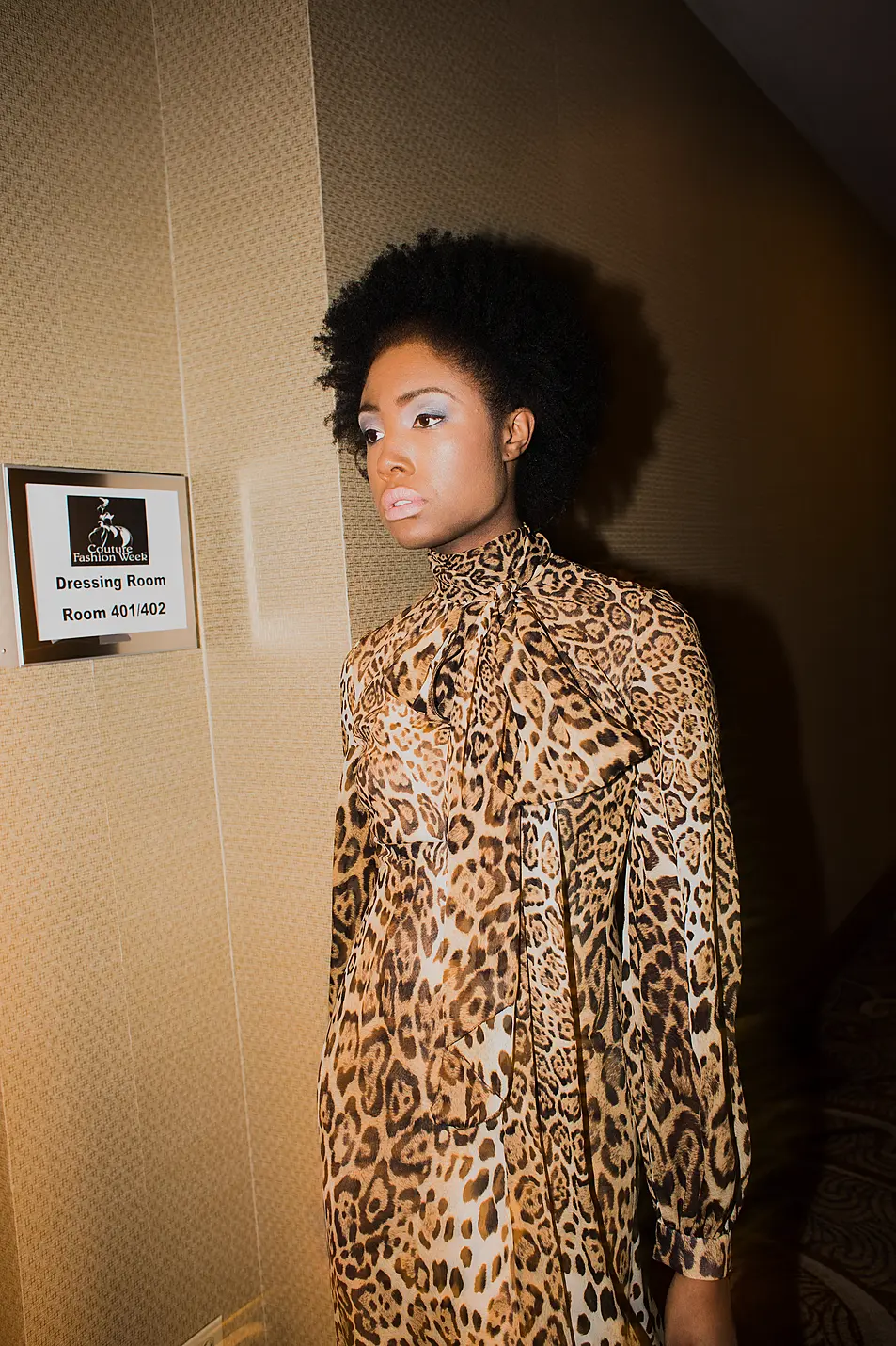 Woman stands in leopard print dress at Fashion Week backstage