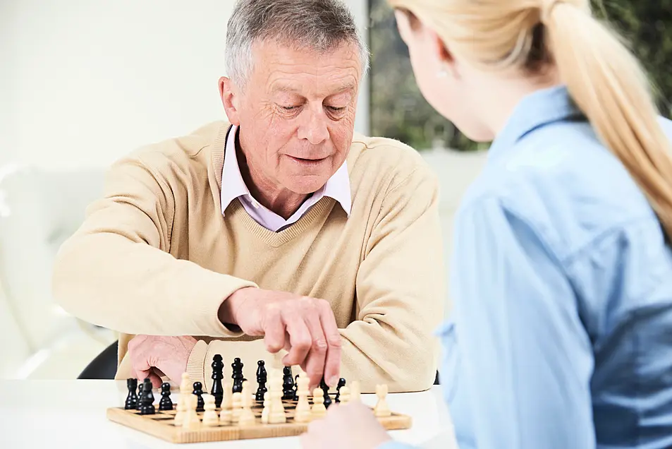 Senior Man Playing Chess With Teenage Granddaughter