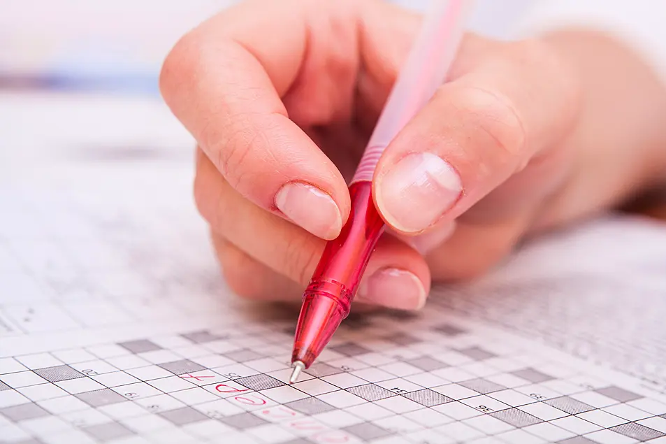 Close-up picture of female hand doing crossword 