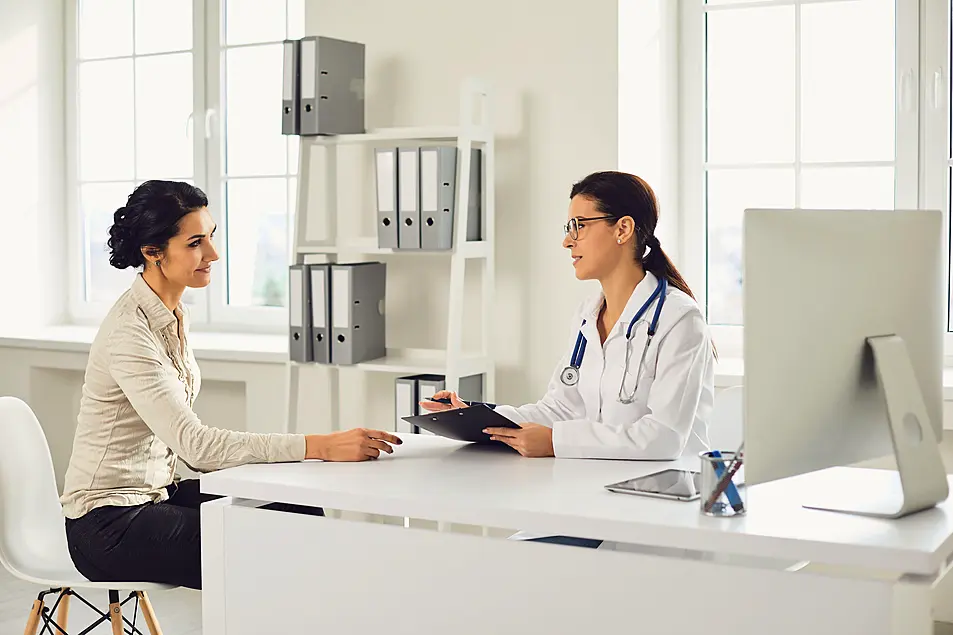 A young woman patient sat down having a discussion with a female doctor in a clinic 