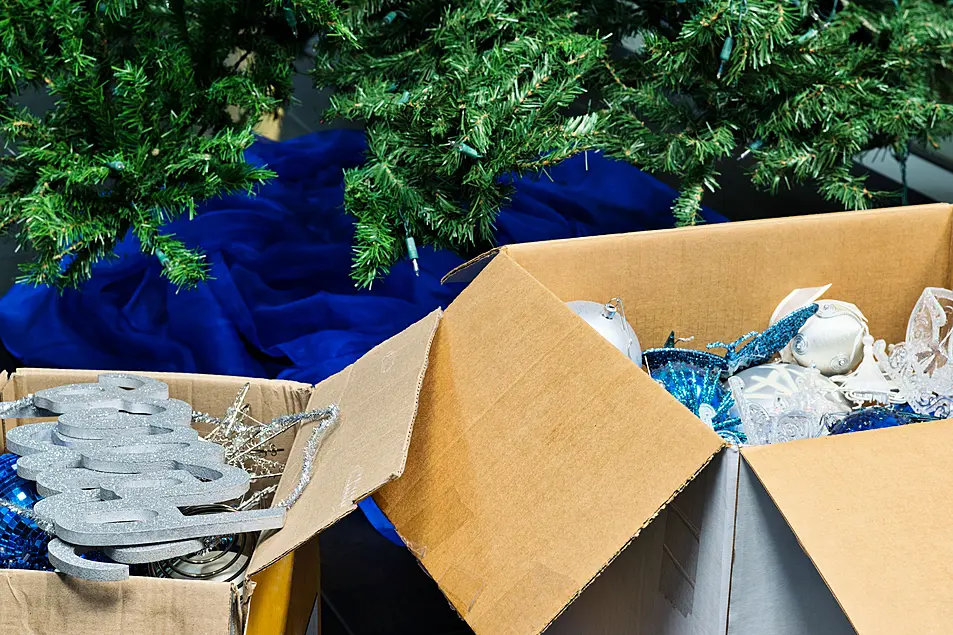 Boxes full of Christmas decorations in front of an empty tree 