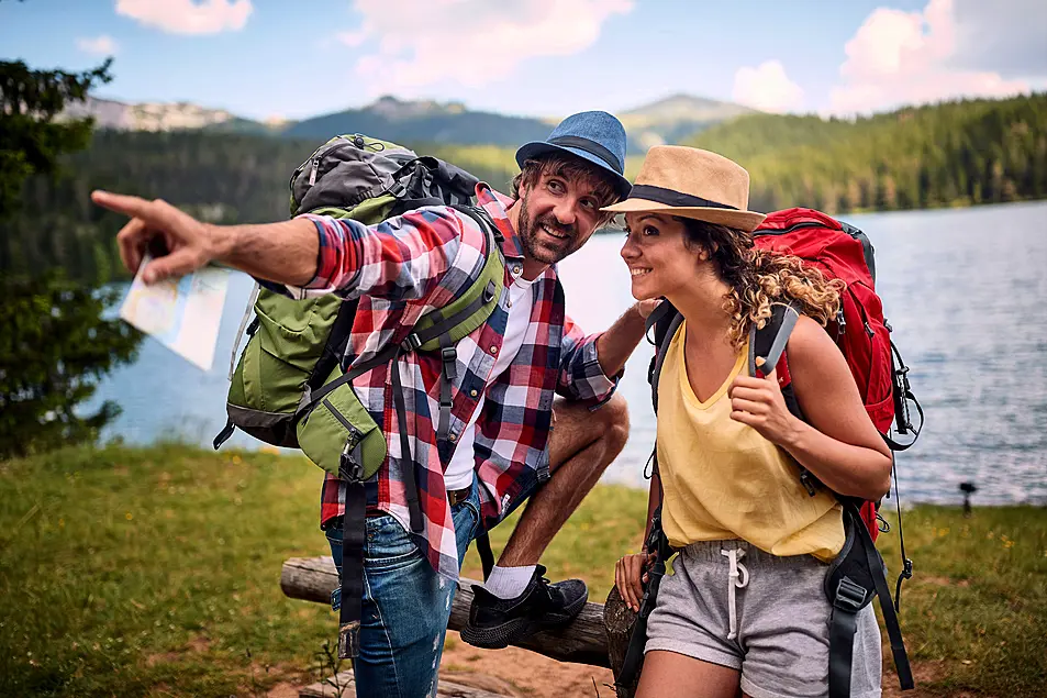 Man and woman with backpacks chatting on a hike 