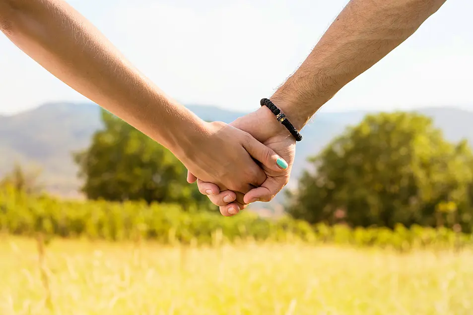 Couple holding hands with romantic view at the sunlit field