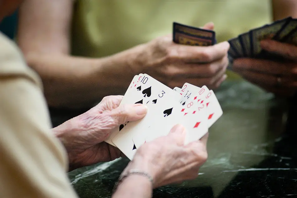 A senior woman holding cards while playing Bridge 