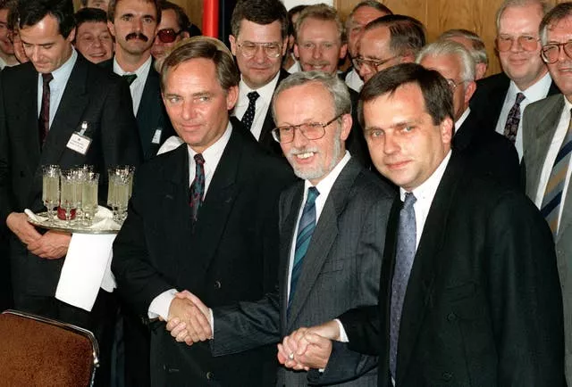 Then-West German secretary of state Wolfgang Schaeuble, left, his East German counterpart Guenther Krause, right, and East German prime minister Lothar de Maizire, centre, symbolically holding hands following the signing of the German unification treaty in East Berlin on August 3 1990 