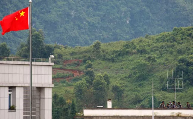 Myanmar government troops stand on a rooftop on the Myanmar side, near a Chinese flag from the Chinese border town of Nansan in southwestern China’s Yunnan province