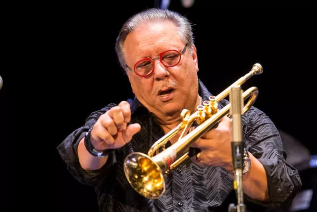 Man in a grey shirt plays the trumpet