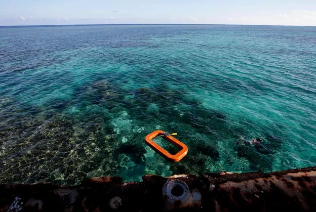 A Philippine Marine, right, swims in the waters of Second Thomas Shoal in the South China Sea