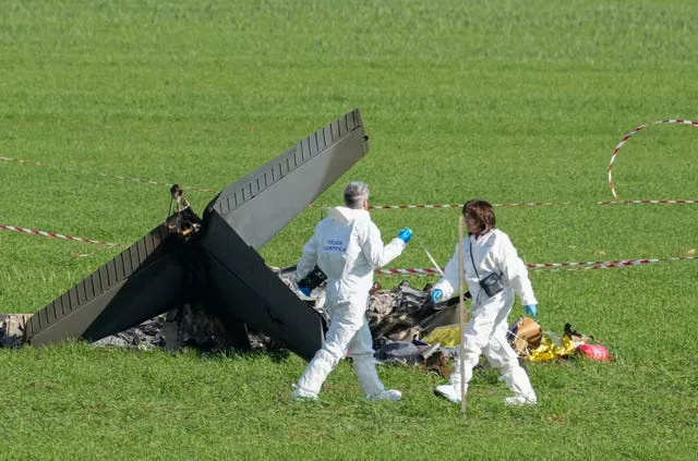 Forensic experts inspect the burned remains of the U-208 aircraft that crashed in a field