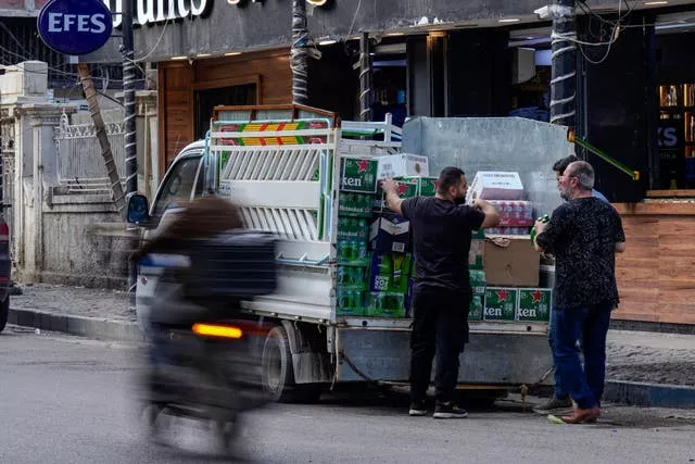Men deliver beer to a booze shop in Baghdad