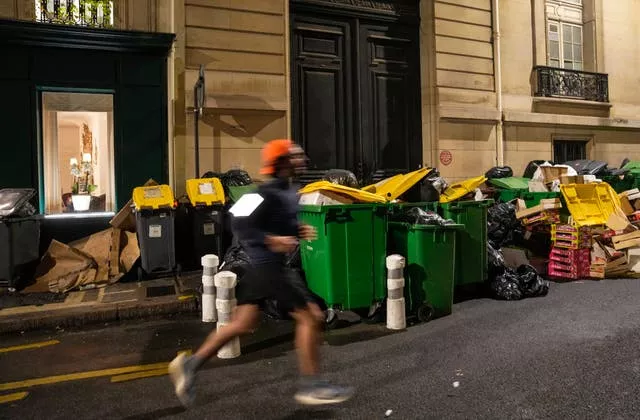 A man jogs past uncollected rubbish bins in Paris