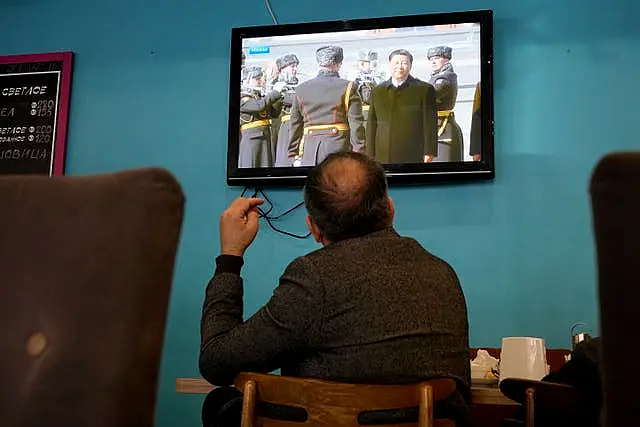 A TV screen displays Chinese President Xi Jinping attending an official welcome ceremony upon his arrival at the Vnukovo-2 government airport outside Moscow, in a cafe in St Petersburg, Russia 