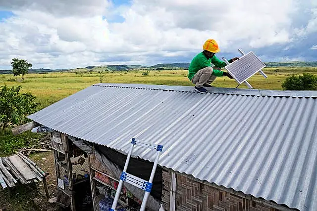 Antonius Makambombu, a worker of Sumba Sustainable Solutions, performs maintenance work on a solar panel on the roof of a customer’s shop in Laindeha village on Sumba Island, Indonesia