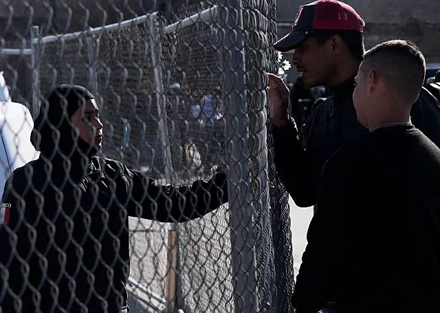 Migrants ask a member of the Mexican National Guard if there is any new information available regarding the victims of the fire 