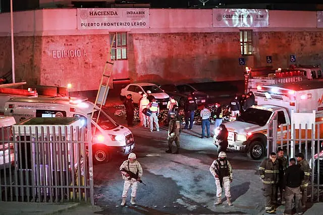 Paramedics and security forces work amid the covered bodies of migrants who died in the fire at the immigration detention centre in Ciudad Juarez, Mexico 