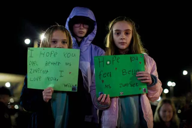 Willow Crawford, left, and her older sister Ava, right, join friend Kaylynn Vestre in expressing their support for Ms Zwerner during a candlelight vigil