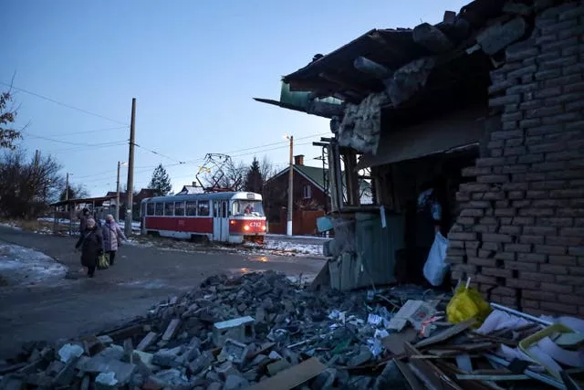 People walk past a damaged part of a house after what Russian officials in Donetsk said was a shelling by Ukrainian forces