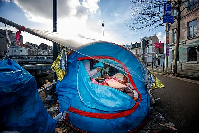 Two men share a meal in a makeshift tent camp outside the Petit Chateau reception centre in Brussels in January