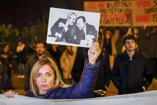 Uma mulher exibe uma fotografia que mostra os principais promotores antimáfia Giovanni Falcone, à esquerda, e Paolo Borsellino