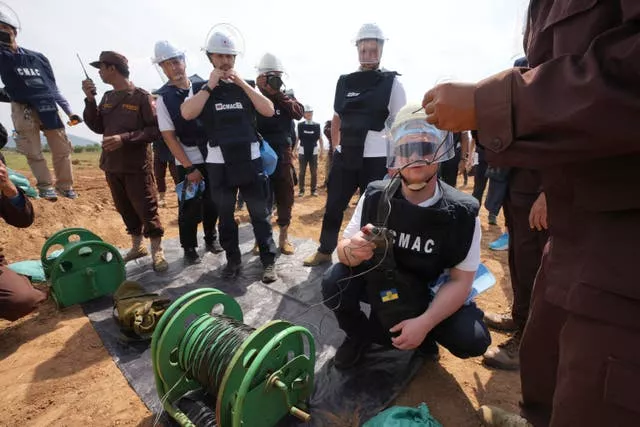 A Ukrainian deminer, second from right, listens to a Cambodia Mine Action Centre worker before a controlled explosion in the mine field at Preytotoeung village in Battambang province