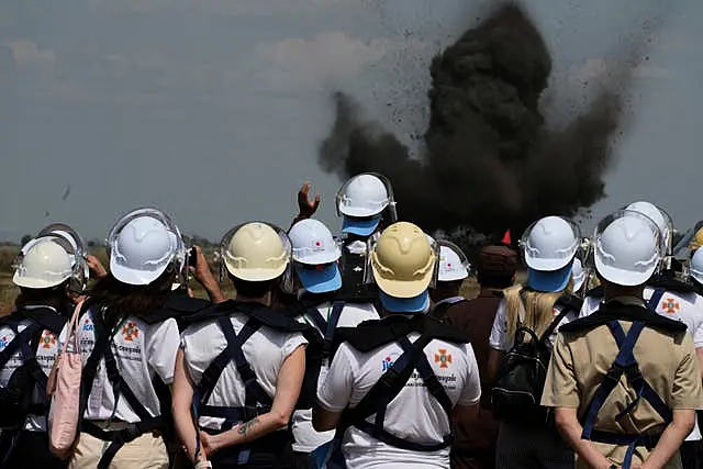 Ukrainian deminers view a controlled bomb explosion at a mine field in Preytotoeung village, Battambang province