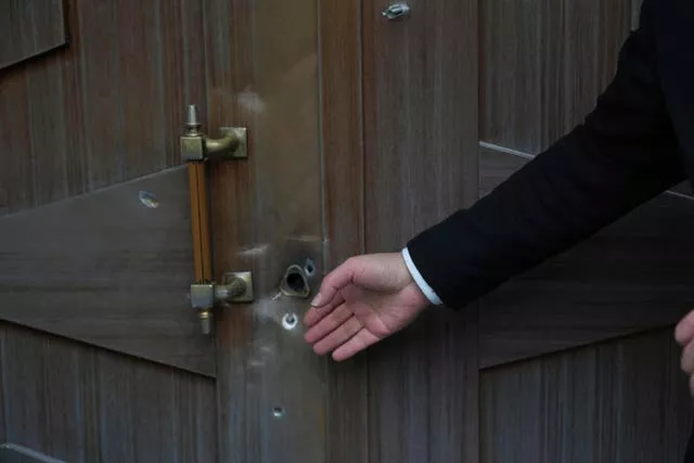 A man gestures at bullet holes left after an attack at the Azerbaijan embassy in Tehran, Iran