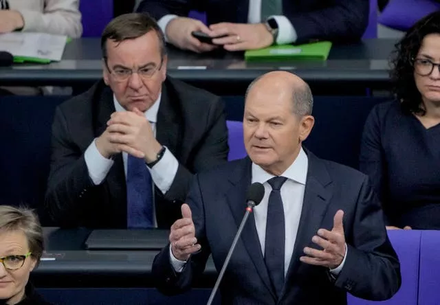 German Chancellor Olaf Scholz, right, speaks to legislators in the German parliament Bundestag in Berlin