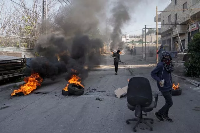 Masked Palestinian demonstrators burn tyres in a protest against a deadly Israeli army raid at Aida Refugee camp, in the West Bank city of Bethlehem 