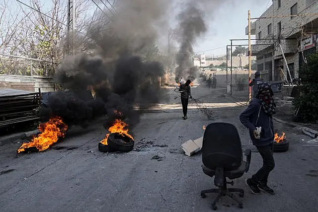 Masked Palestinian demonstrators burn tyres in a protest against a deadly Israeli army raid at Aida Refugee camp, in the West Bank city of Bethlehem 