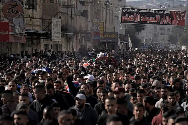 Mourners carry the bodies of eight Palestinians, some draped in the flag of the Islamic Jihad militant group, during a joint funeral in Jenin on Thursday January 26 2023