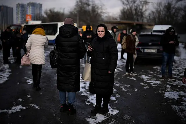 People wait on a street blocked by police after a rocket attack in Kyiv, Ukraine