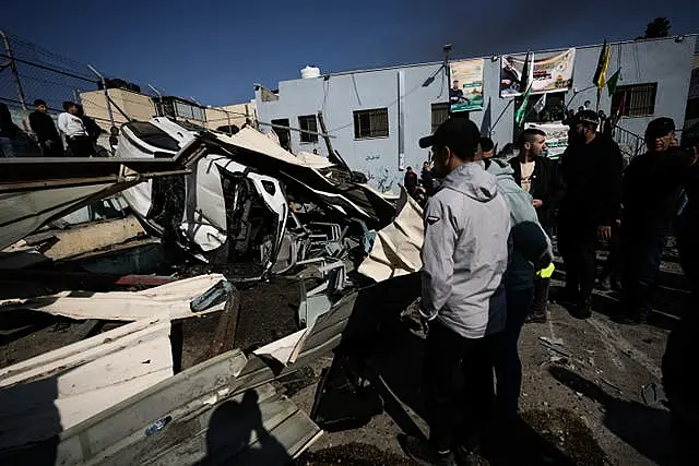 Palestinians inspect the site of a damaged building after an Israeli forces raid in Jenin