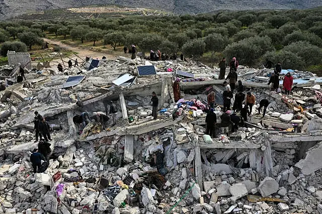 Civil defence workers and residents search through the rubble of collapsed buildings in the town of Harem near the Turkish border, Idlib province, Syria