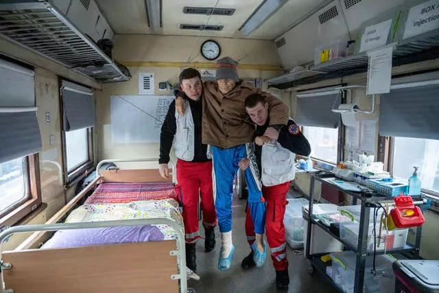 MSF workers carry a man inside the MSF medical train that evacuates patients from near the front lines of the fighting to safer areas at the train station in Pokrovsk, Ukraine