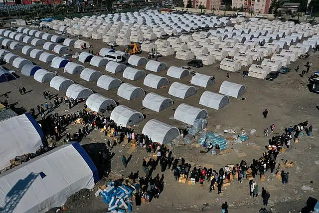 People who lost their houses in the earthquake, queue for aid supplies at a makeshift camp in Iskenderun city, southern Turkey