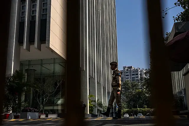 An armed security person stands stand guard at the gate of a building housing BBC office in New Delhi