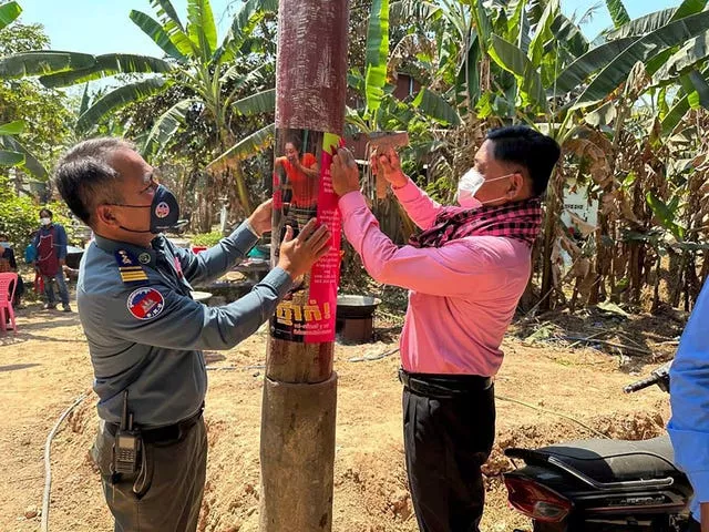 A Cambodian animal health officer, right, and a military police officer place posters about awareness of H5N1 virus threats in Prey Veng eastern province 