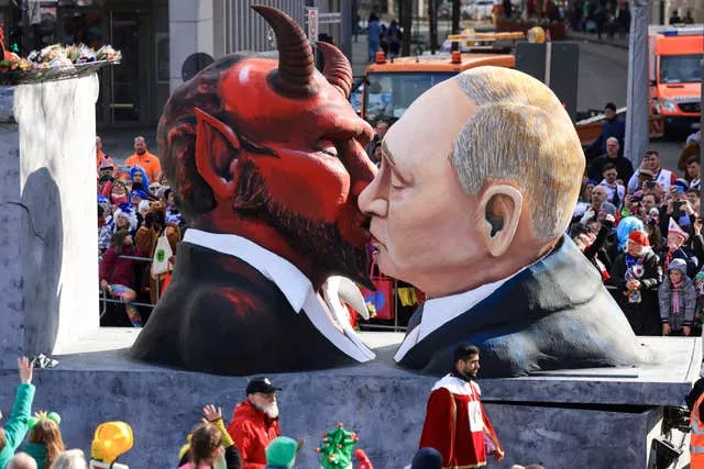 A float with a depiction of Russian President Putin kissing the devil rides in the parade in Cologne, Germany 