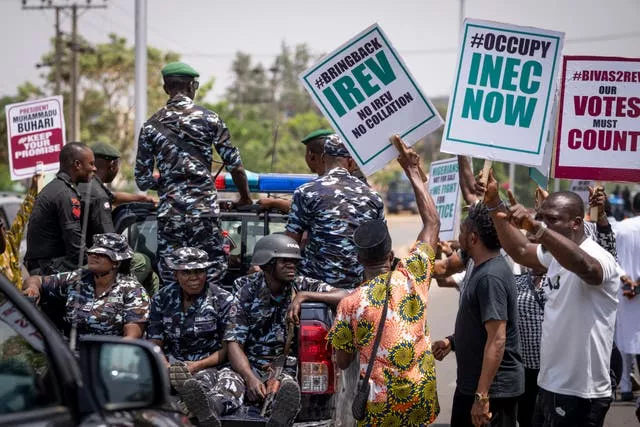 A police truck drives past demonstrators accusing the election commission of irregularities and disenfranchising voters, as they make a protest in Abuja, Nigeria
