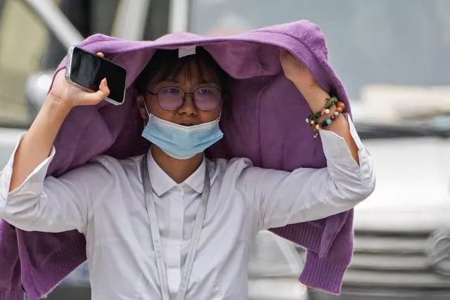 A woman tries to shield herself from the sun in Beijing 
