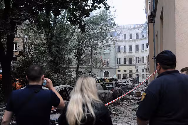 People watch as emergency service workers continue to search for victims after a Russian missile attack in Lviv,