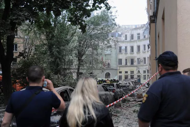People watch as emergency service workers continue to search for victims after a Russian missile attack in Lviv,