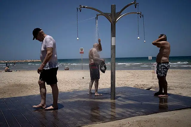 Men shower at a public beach as they take refuge from a summer heatwave in Tel Aviv on Thursday