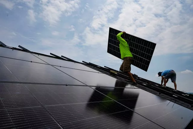 A person carries a panel at a solar farm in the US 
