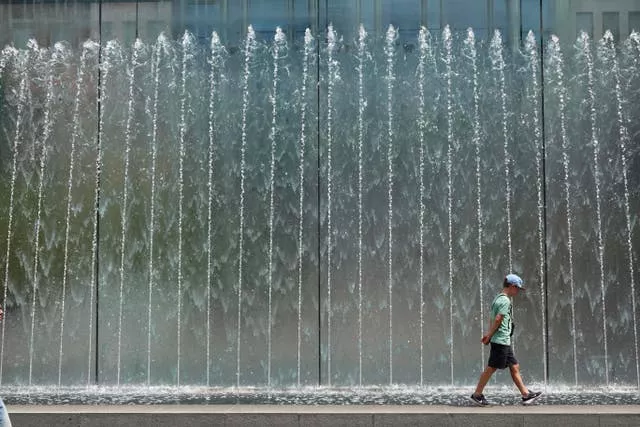 A boy walks on the edge of a fountain in Milan 