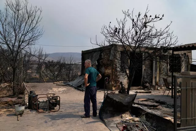 A man stands by a burnt house 