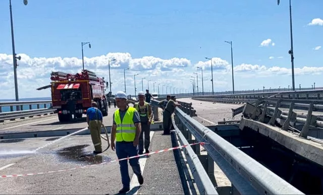 Employees work at the damaged parts of an automobile link of the Crimean Bridge connecting Russian mainland and the Crimean peninsula over the Kerch Strait